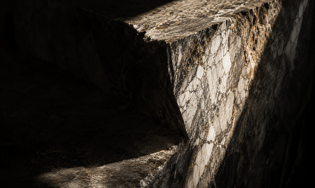 Editorial macro photograph of natural stone illuminated by dramatic light, illustrating how timeless materials become more beautiful with age.