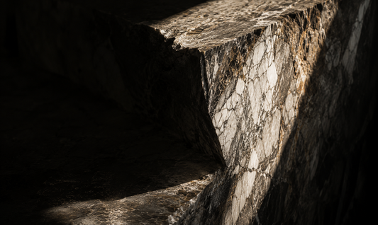 Editorial macro photograph of natural stone illuminated by dramatic light, illustrating how timeless materials become more beautiful with age.