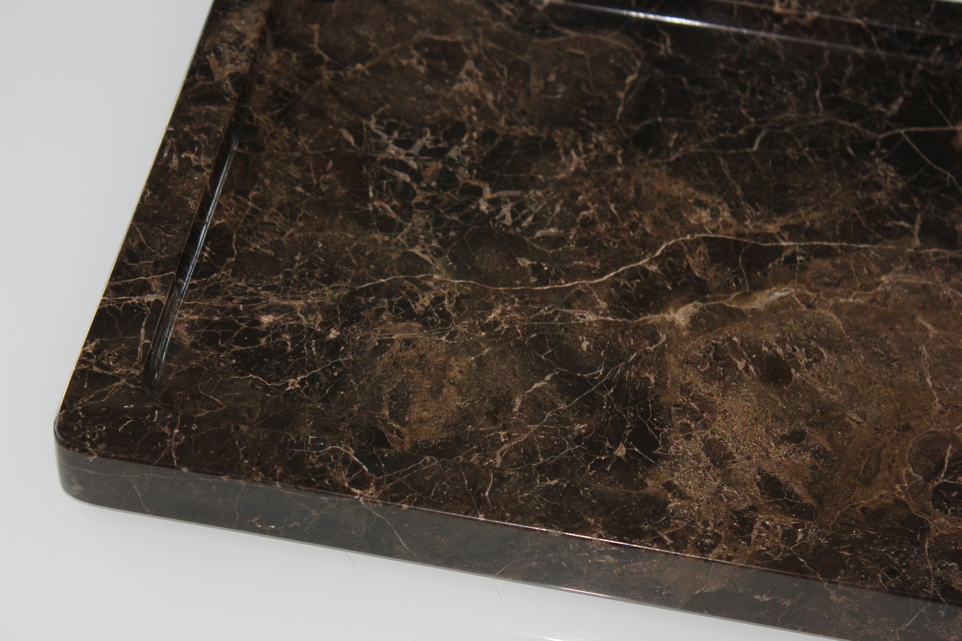 Close-up of the rounded polished corner of The Monolith Dark Emperador tray.