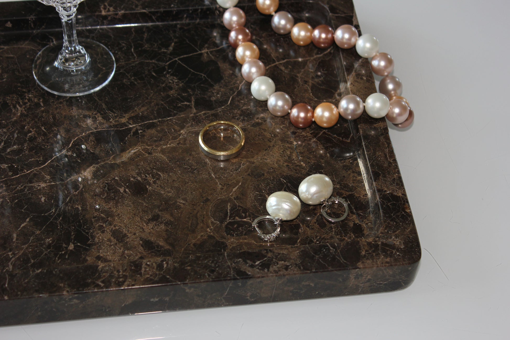 Jewellery arranged on The Monolith tray in polished Dark Emperador marble.