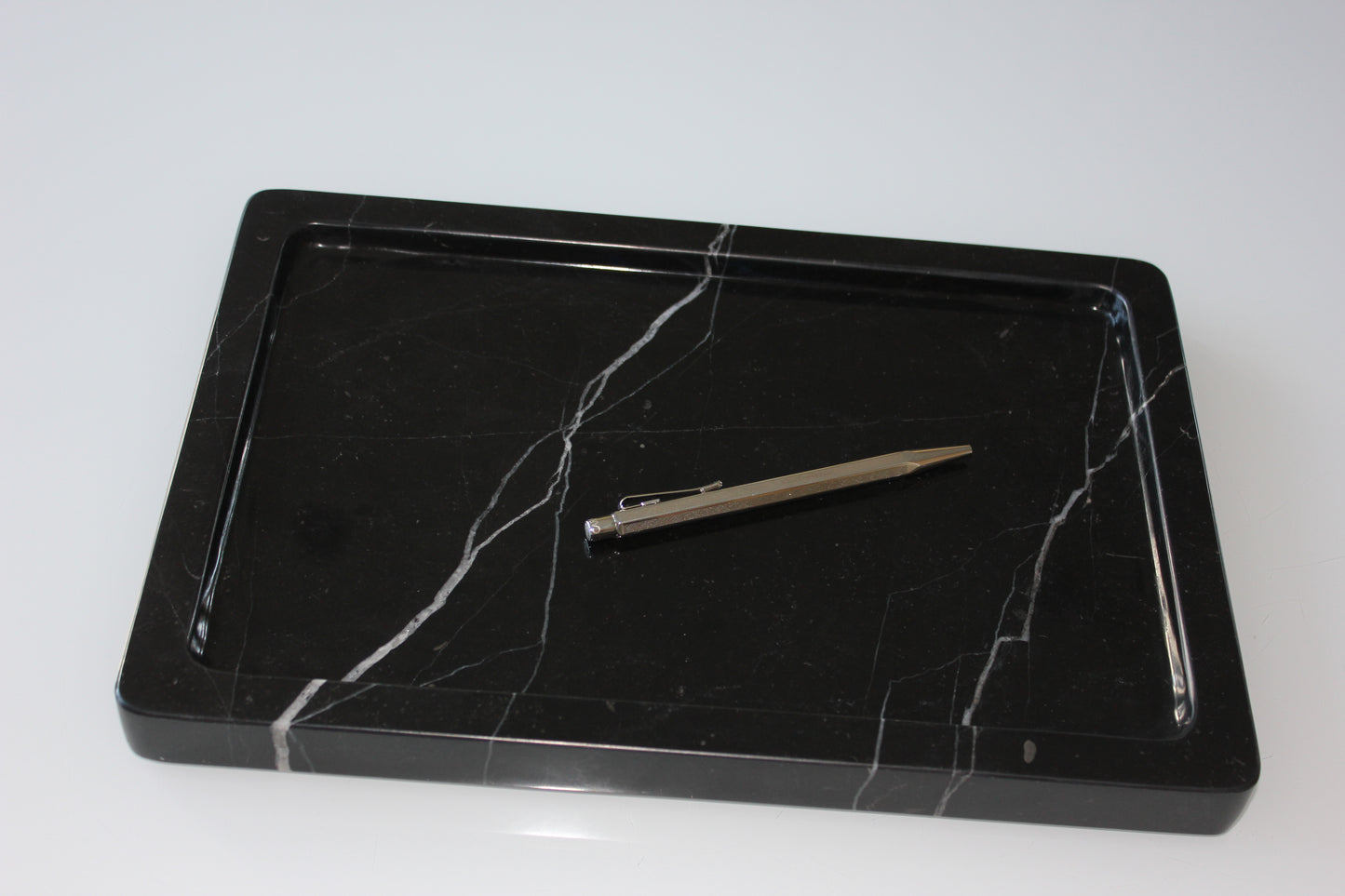 Minimal workspace with The Monolith tray in Nero Marquina marble and a silver pen.