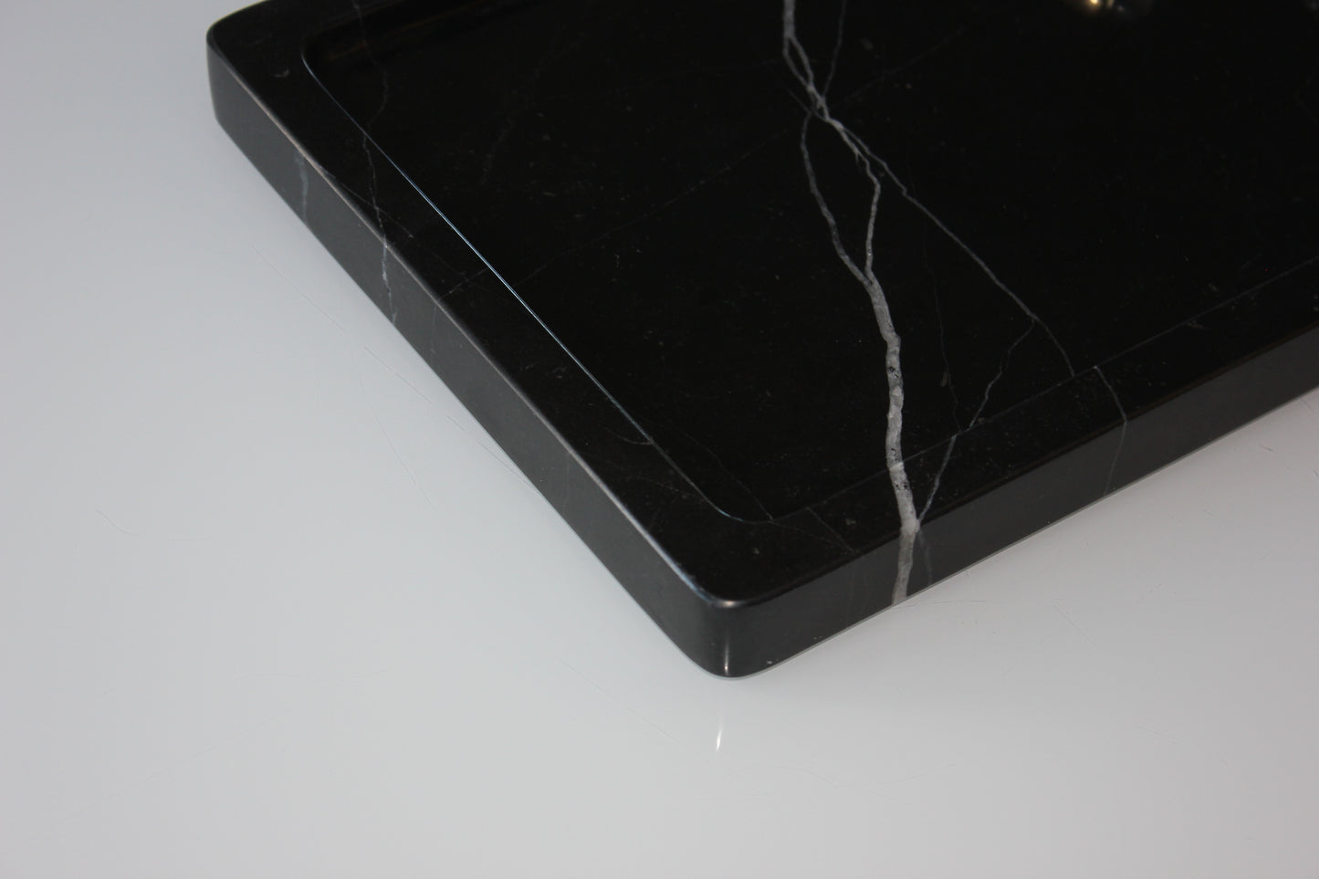 Close-up of the rounded corner and polished edge of The Monolith Nero Marquina tray.