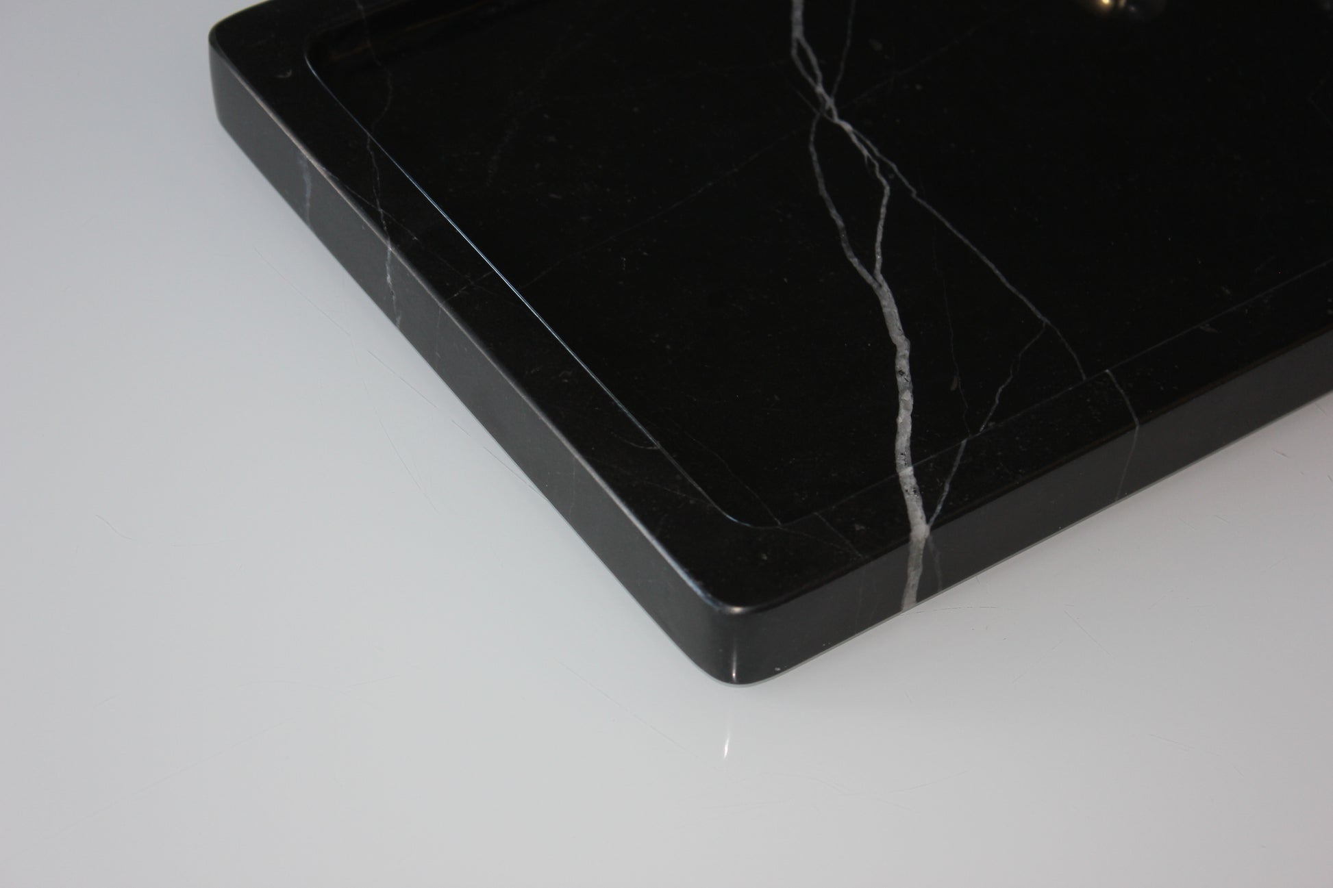 Close-up of the rounded corner and polished edge of The Monolith Nero Marquina tray.